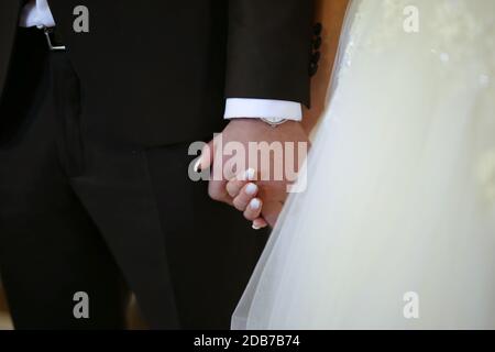 Tema di nozze, tenendo le mani sposi novelli. Lo sposo e lo sposo si tengono le mani l'uno dell'altro. Coppia amorevole Foto Stock