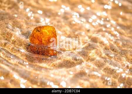 Ambra su una spiaggia del Mar Baltico nel surf Foto Stock