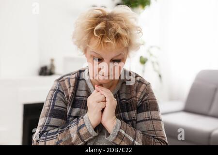 Religiosa fedele donna di mezza età che prega con speranza fede tenendo le mani aggrappate insieme a namaste a casa la mattina, vecchia signora matura credente Foto Stock