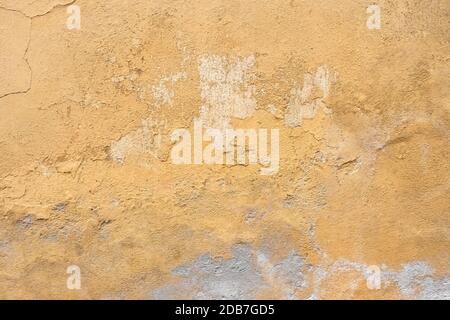 Grunge parete intonaco con sfondo giallo graffiato. Vecchio muro con buccia color palude stucco texture. Carta da parati vintage. Decadimento e crepe. Abstra ruvida Foto Stock
