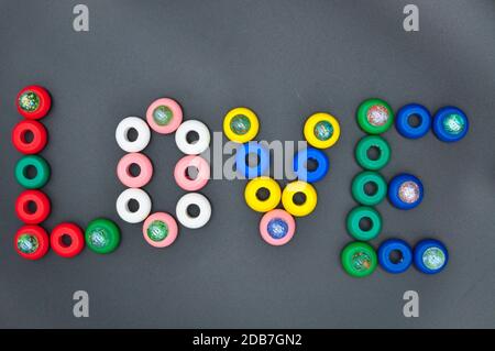 La parola amore scritto con cerchi di legno di molti colori su sfondo nero Foto Stock