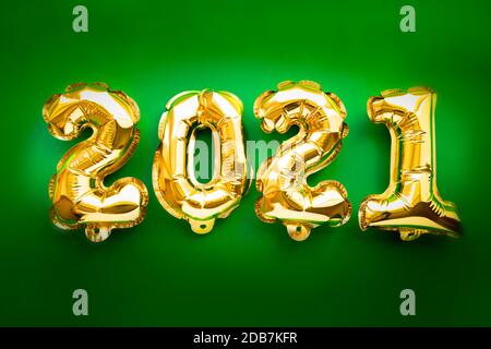 Felice celebrazione del nuovo anno 2021. Palloncini oro numero 2021 su sfondo verde festivo. Disposizione piatta Foto Stock
