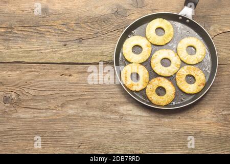 Pinaple alla griglia in una padella su vecchio tavolo in legno d'annata. Gustoso antipasto o contorno dolce. Fritto poco con poco ma di burro. Spazio di copia. Foto Stock