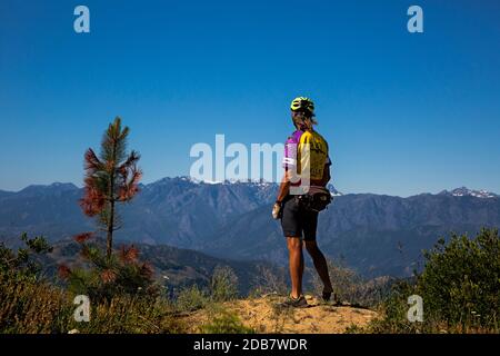 WA18136-00...WASHINGTON - ciclista che guarda la vista dalla affluenza La Chumshick Mountain Road con il Monte Stuart e la piccola Annapurna in vista Foto Stock