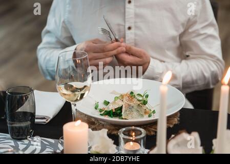 Uomo che mangia insalata di Calamari croccante con lattuga, limone e asparagi Foto Stock