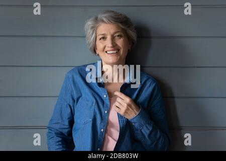 Head shot ritratto sorridente donna matura su sfondo grigio di legno Foto Stock