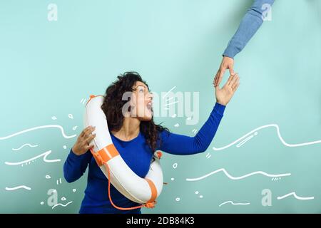 La donna sta affogando e chiede aiuto con un messaggio di un foglio di carta. Sfondo ciano Foto Stock