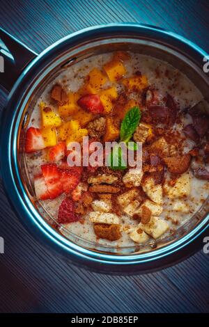 Foto di primo piano di una farinata d'avena condita con cannella, mescolata con latte di cocco, frutta e noci, gustosa colazione, sana alimentazione biologica, miglior cibo per Foto Stock