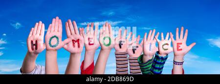 Kids Hands Holding parola colorata tedesco Homoffice significa lavoro da casa. Cielo blu come sfondo Foto Stock