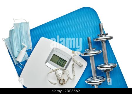 Attrezzature sportive, bilance, maschere mediche e igienizzatore su sfondo bianco. Vista dall'alto, spazio di copia. Fitness. Periodo di isolamento. Peso e controllo della salute Foto Stock