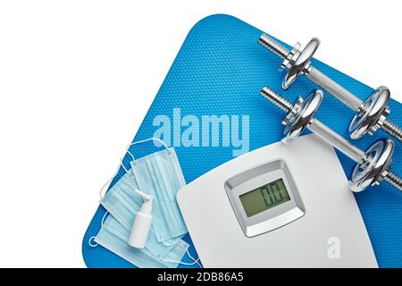 Attrezzature sportive, bilance, maschere mediche e igienizzatore su sfondo bianco. Vista dall'alto, spazio di copia. Fitness. Periodo di isolamento. Peso e controllo della salute Foto Stock