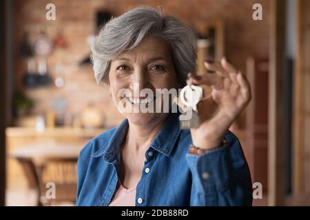 Ritratto della testa sorridente donna matura che tiene la chiave da casa Foto Stock