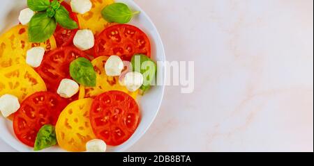 Mozzarella, basilico e pomodoro su piatto bianco. Primo piano della vista superiore. Foto Stock
