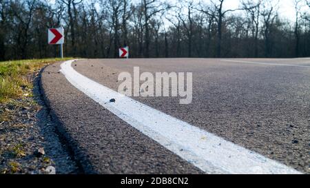 Svolta a destra di una strada asfaltata con segnaletica orizzontale Foto Stock