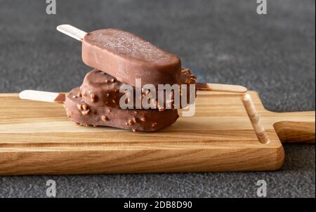 Gelaterie alla vaniglia ricoperte di cioccolato sulla tavola di legno Foto Stock