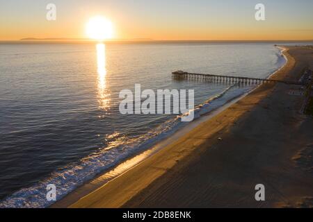 Vista aerea che guarda sulla costa della contea di Orange come il sole si affaccia sull'Oceano Pacifico e sul molo di Balboa Foto Stock