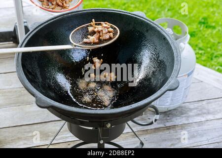 Frittura di pancetta in calderone sul fuoco all'aperto in estate. Foto Stock