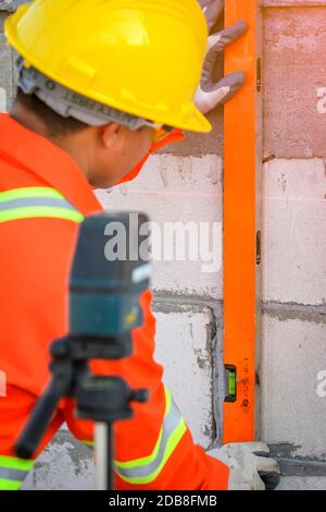 Operaio di costruzione che usa una livella di spirito su un luogo di costruzione, Tailandia Foto Stock