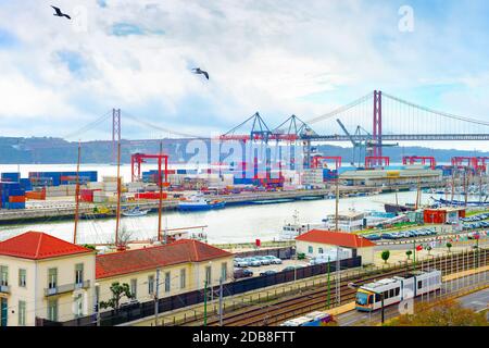 Gabbiani sul porto commerciale di Lisbona, container di navi e gru per il trasporto merci, skyline con il 25 aprile Ponte e fiume Tago, Portogallo Foto Stock