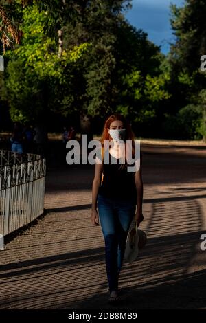 Donna che indossa una maschera a piedi in una Villa Borghese, Roma, Lazio, Italia Foto Stock