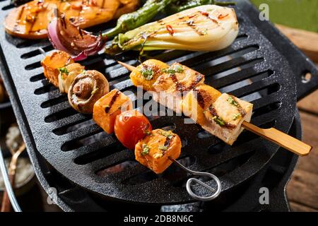 Un primo piano di spiedini di verdure gourmet su una griglia sopra i calli caldi. Foto Stock