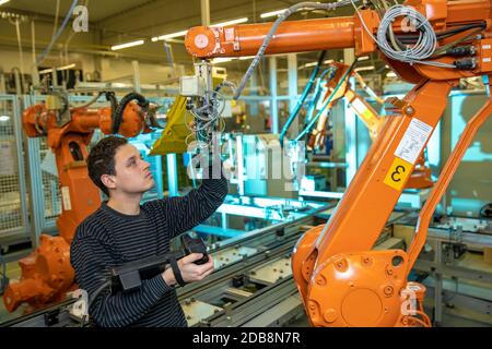 programmazione di bracci robot per un nuovo prodotto da parte di un tecnico di produzione. Foto Stock