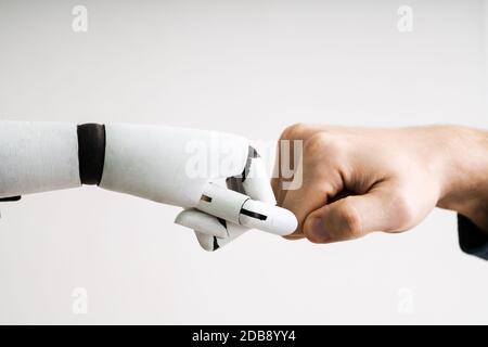 Il robot e la mano umana facendo Fist Bump su sfondo grigio Foto Stock