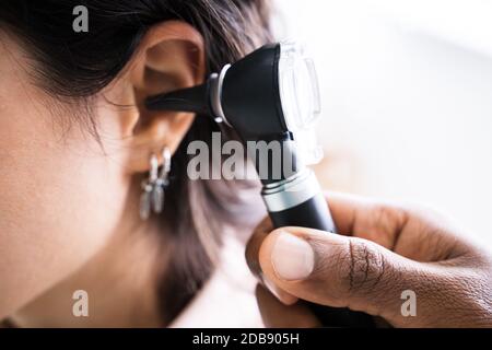 Close-up di medico donna esaminando orecchio del paziente con otoscopio Foto Stock