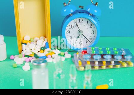 Siringa con fiale di vetro e farmaci pillole farmaco. Sullo sfondo c'è una scatola di legno e una mela gialla. Vista frontale. Foto Stock