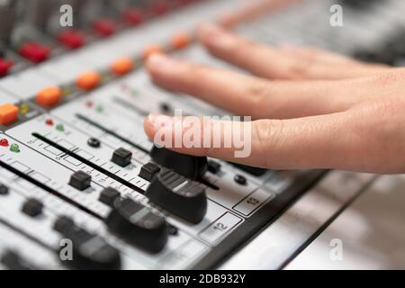 Maschio a mano il fader di comando sulla console. Per la registrazione del suono miscelazione in studio con scrivania da parte di un tecnico o di un produttore di musica . Foto Stock