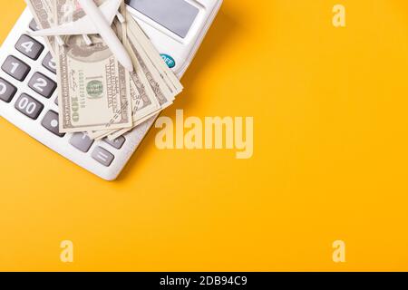 Aprile dell'anno è giorno di imposta, calcolatore di primo piano di primo piano di vista e soldi del dollaro, sul concetto giallo di preventivo di finanza di affari di fondo con la copia sp Foto Stock