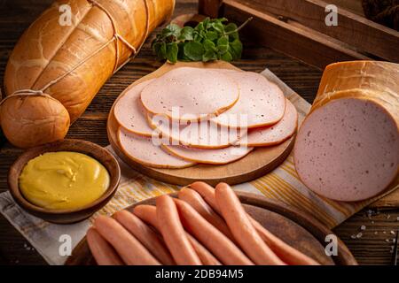 Deliziose carni deli e salsicce Wiener sul tagliere in legno Foto Stock