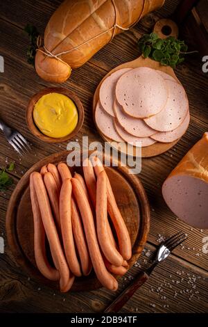 Affettati di pollame e salsicce calde con senape su fondo di legno Foto Stock