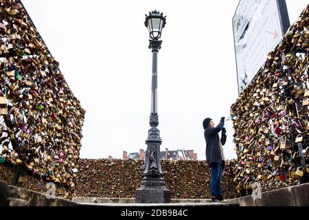Parigi, Francia - Marzo 2018: giovane donna di scattare una foto dell'amore si blocca a Pont Neuf a Parigi Foto Stock