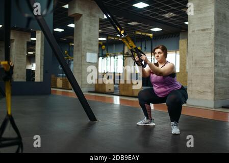 Donna in sovrappeso che fa esercizio di stretching in palestra, allenamento attivo. La persona femminile obesa lotta con il peso in eccesso, allenamento aerobico contro l'obesità, Foto Stock