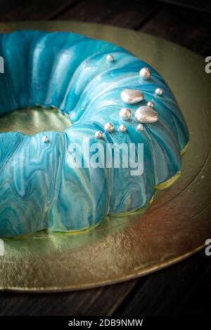 Torta di mousse decorata in stile marino coperta da smalto a specchio blu e decorazioni in argento. Foto Stock