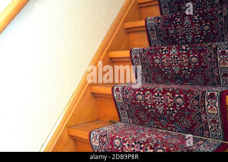 Scale con striscia di moquette a motivi rossi, vecchia scala in legno d'epoca, primo piano di design antico Foto Stock