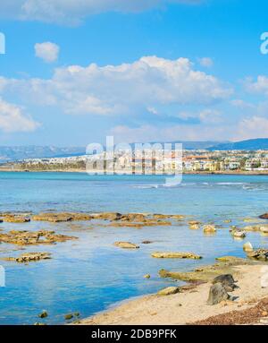 Skyline di Paphos con spiaggia rocciosa in primo piano, Cipro Foto Stock