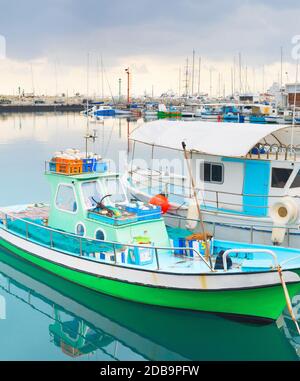 Coloratissime barche di pescatori ormeggiate nel porto di Limassol con ristoranti sul molo, Cipro Foto Stock