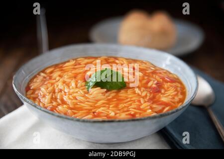 Ciotola di pasta all'orzo e zuppa di pomodoro con basilico Foto Stock