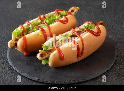 Due hot dog con salsicce alla griglia a bordo di pietra Foto Stock