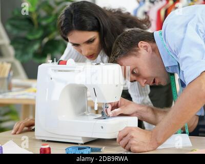 Camera di stilista, il sarto sta controllando l'autenticità della macchina da cucire. Prima di iniziare a lavorare per i clienti che sono in attesa. Foto Stock