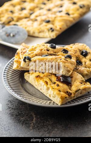 Focaccia italiana fatta in casa. Pasticceria tradizionale italiana con olive nere e pomodori secchi. Foto Stock