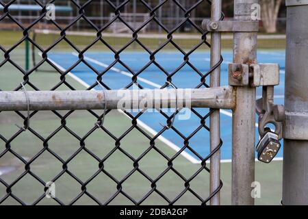 Primo piano del cancello con lucchetto di un campo da tennis con rete in background. Foto Stock