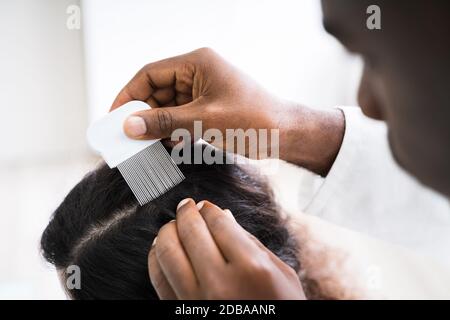 Close-up di persona a mano utilizzando i pidocchi pettine su paziente i capelli Foto Stock