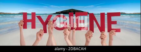 Persone mani in mano Red English Word igiene. Oceano e spiaggia come sfondo Foto Stock