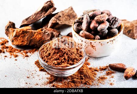 Cacao in polvere organico, cacao in grani, grattugiato di cacao su fondo grigio. Spazio di copia Foto Stock