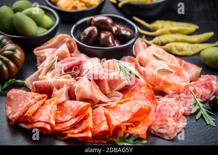 Piatto di antipasti con un misto di salame, prosciutto, chorizo, peperoni, pomodori e olive Foto Stock
