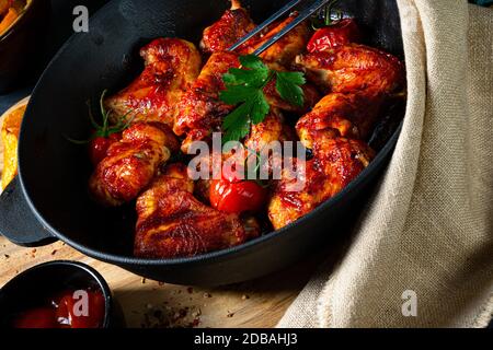 Ali di pollo speziate al miele con spicchi di patate Foto Stock