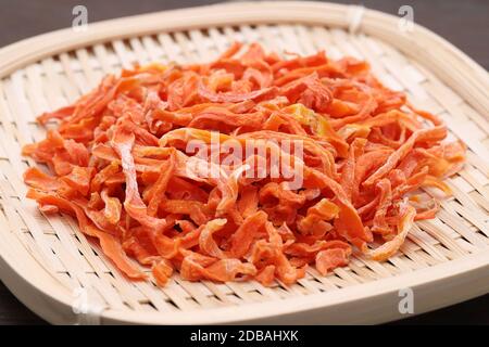 Carote tagliate essiccate in un cesto di bambù su tavola Foto Stock